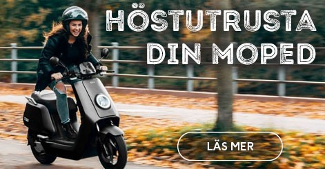 En kvinna kör elmoped i en allé på hösten